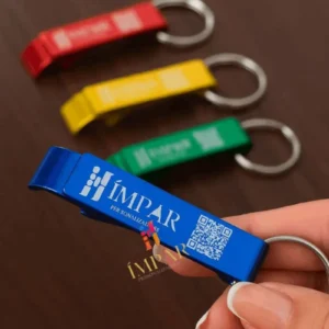 Close-up de uma mão usando o chaveiro abridor para levantar o anel de uma lata de alumínio, protegendo a unha de quem o utiliza.